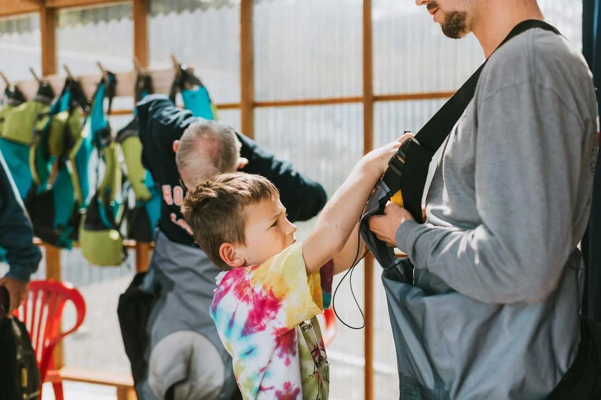 Boy helping man with dry suit